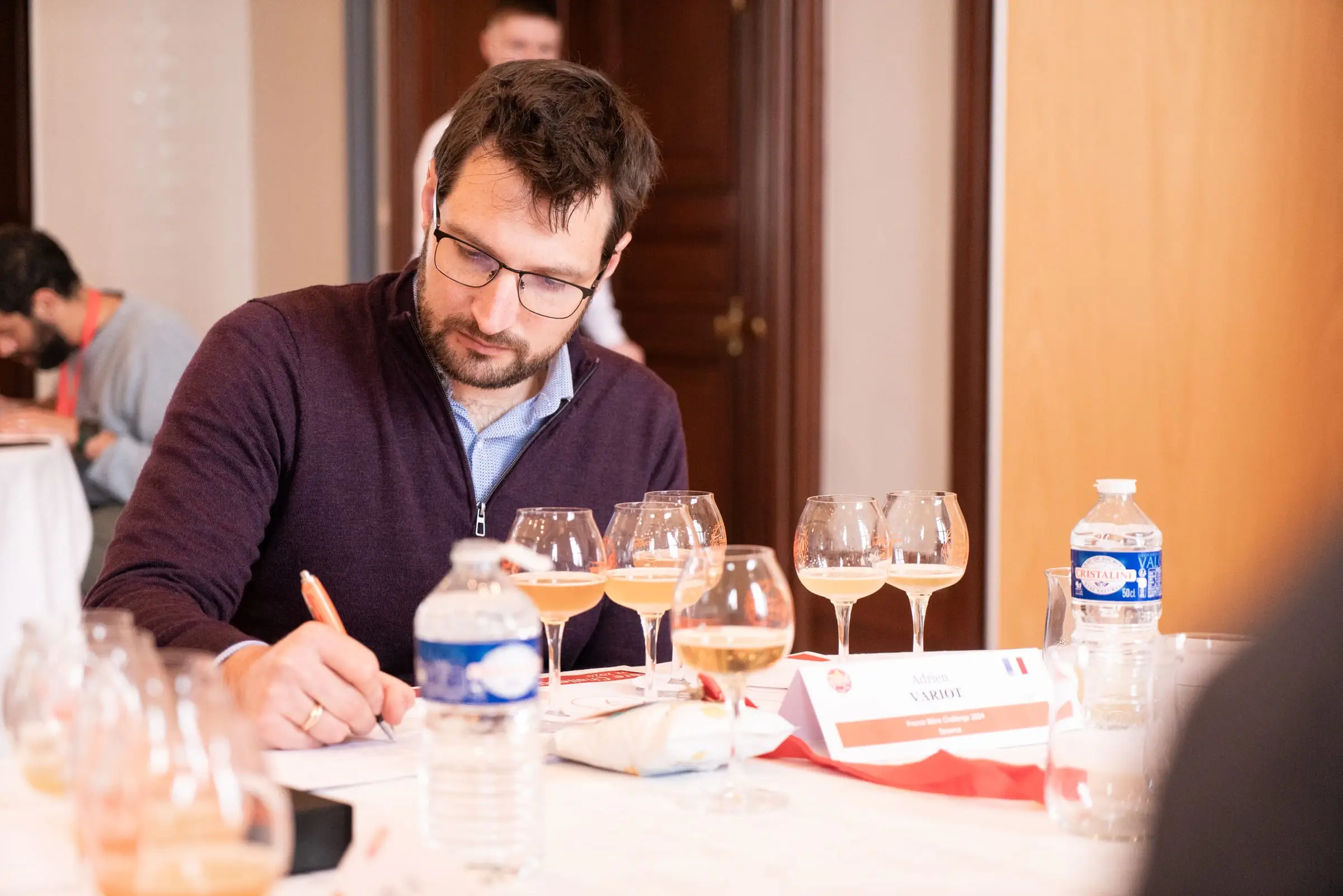 Un juré du France Bière Challenge note sa dégustation devant une série de verres