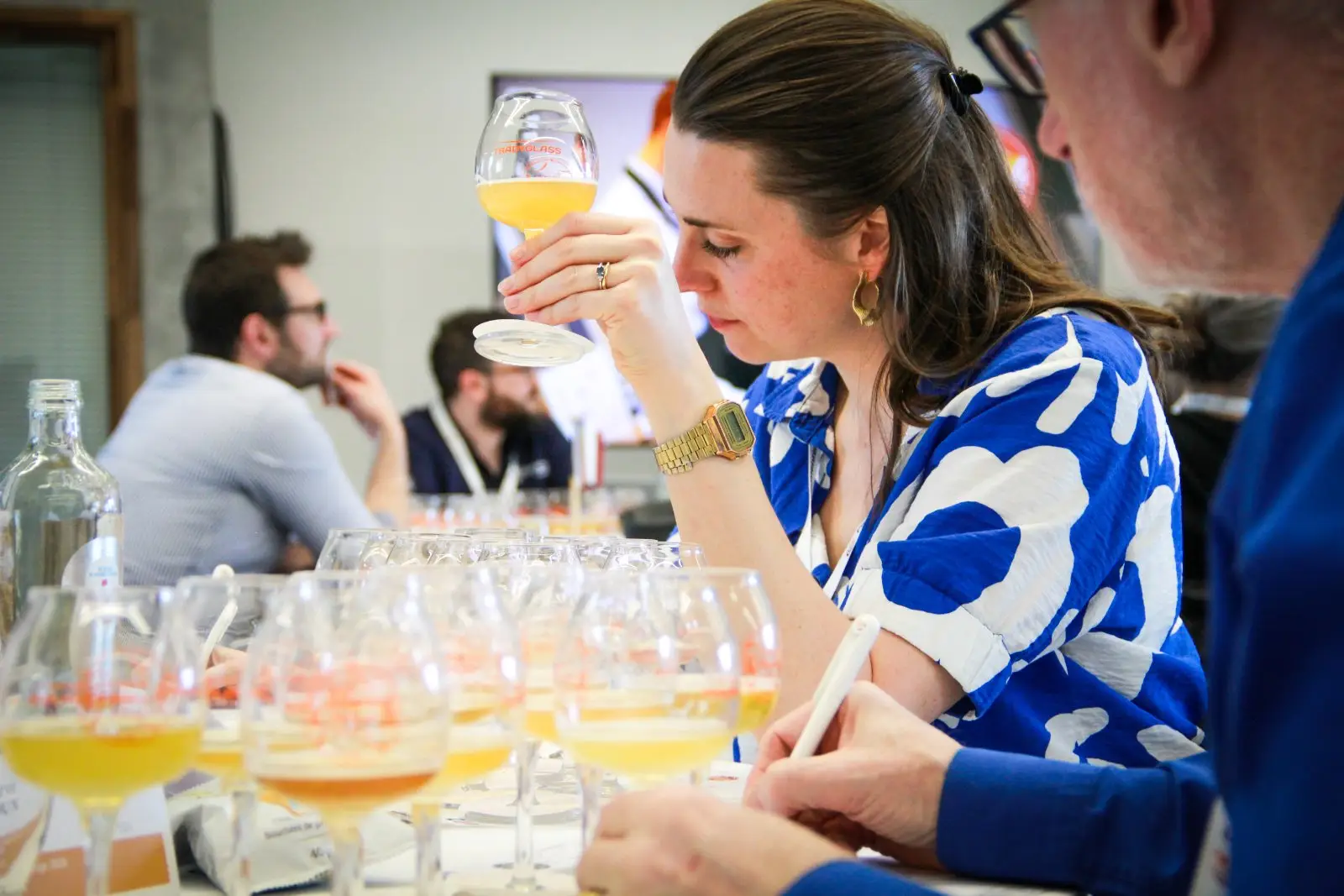 Une jurée examine une bière à l'aveugle, verre levé à la lumière, lors du France Bière Challenge 2026